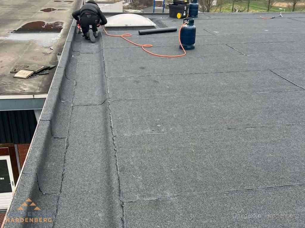 Dakdekker repareert bitumen dakbedekking op groot plat dak in Hardenberg